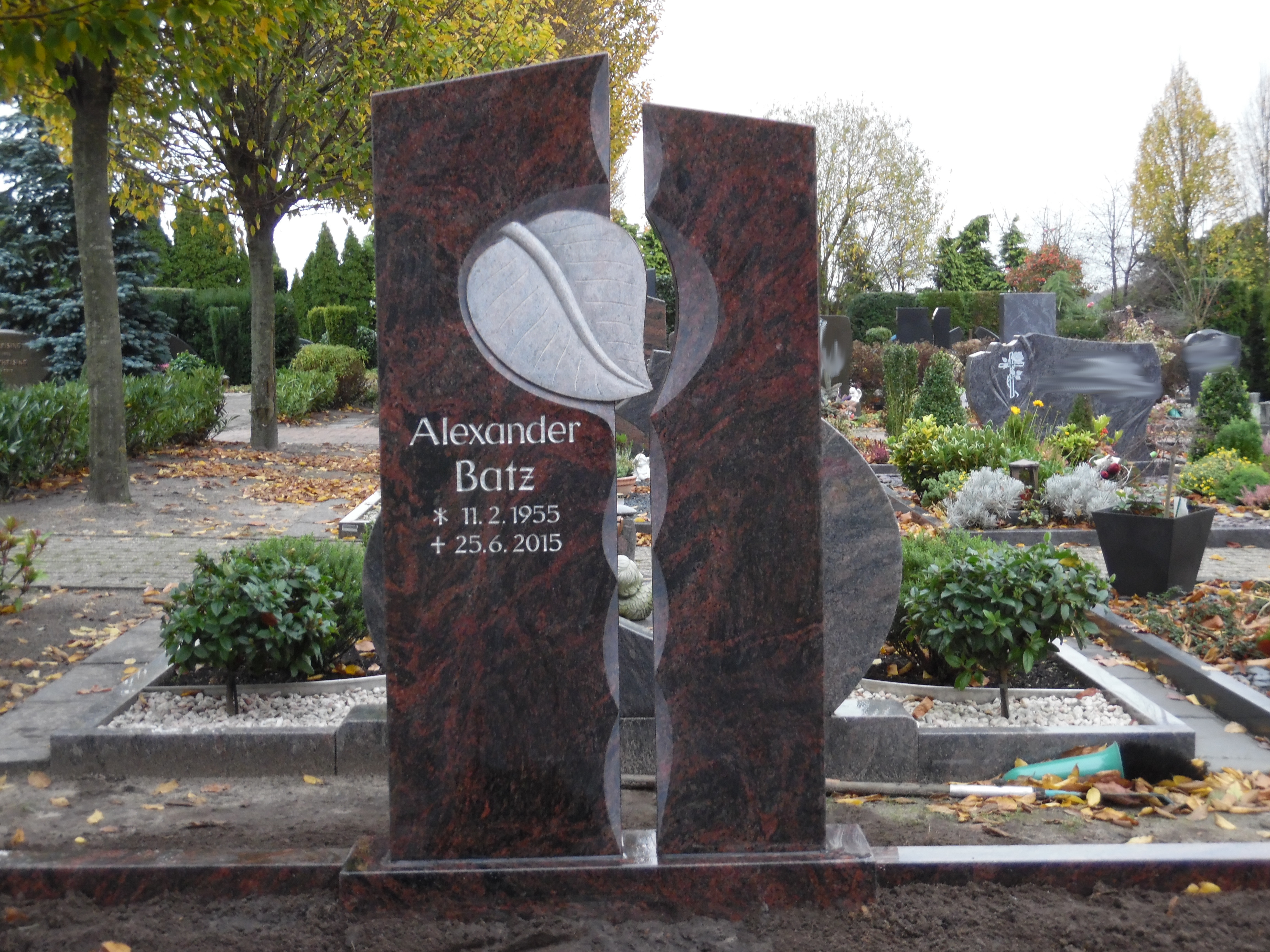Ein rotbrauner Grabstein mit geteiltem Design und silberner Gravur von Alexander Batz