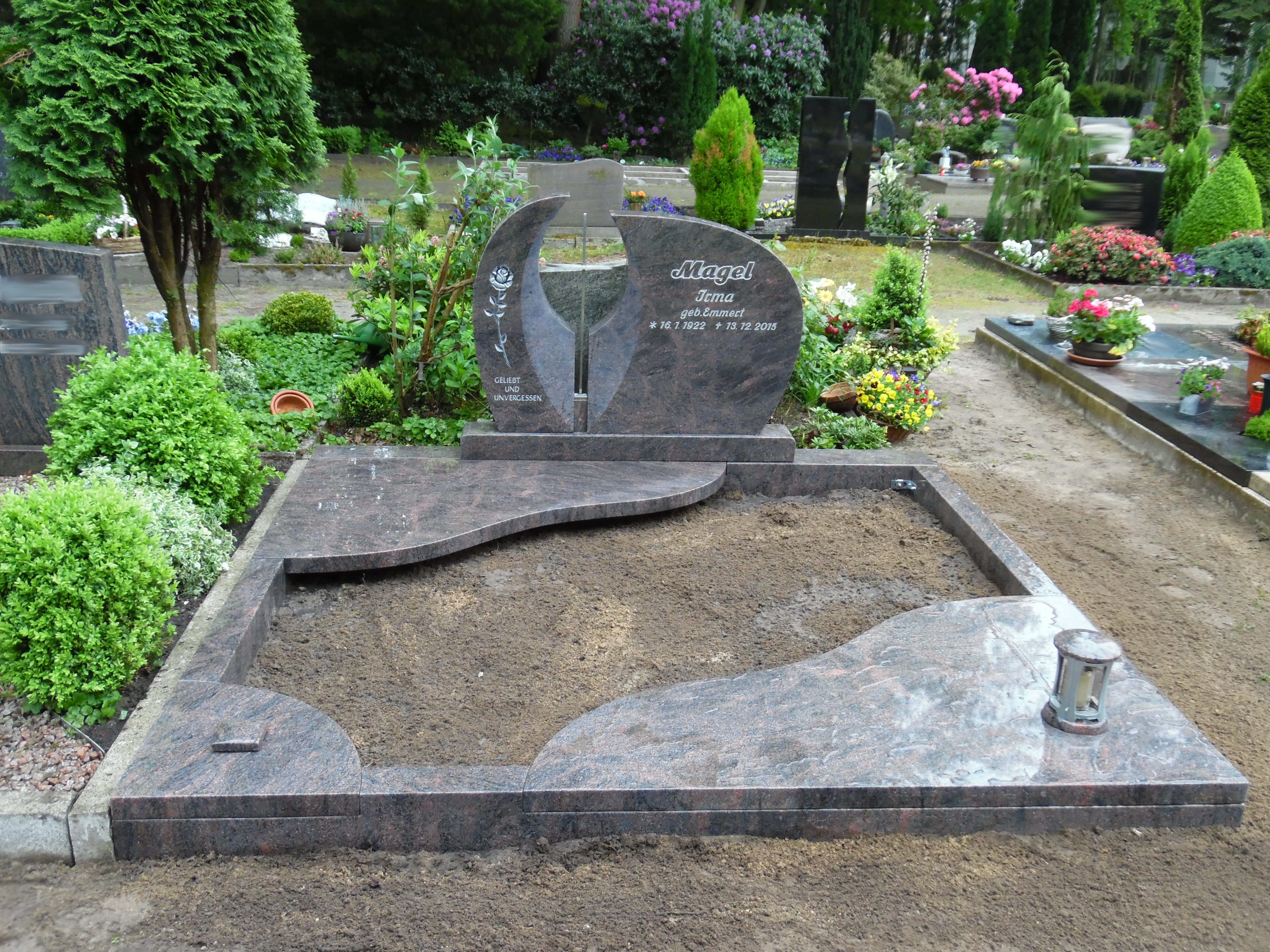 Ein moderner, schwarz-grauer Grabstein mit runden Elementen auf einem Friedhof
